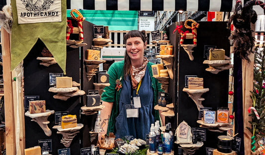 A smiling woman greets you in a market booth filled with wonderful goat milk soap